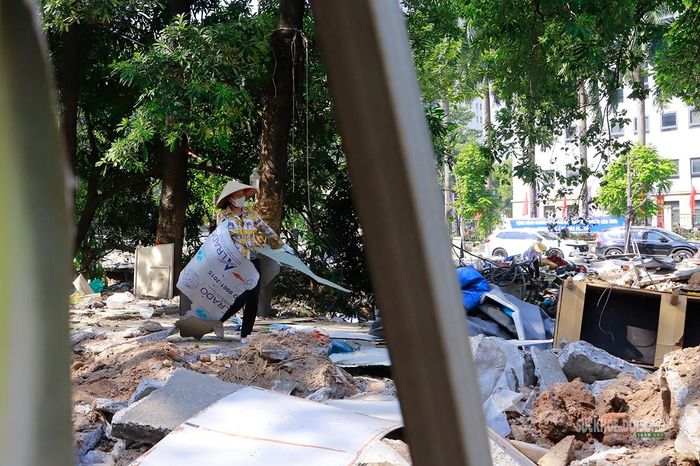 Người dân thu gom những tấm vật liệu còn sót lại tại khu vực vừa tháo dỡ. Ảnh: Tuấn Anh