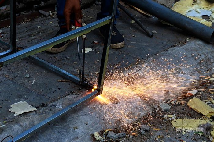 Thợ cơ khí dùng thiết bị cắt kim loại để tháo rời khung sắt. Ảnh: Tuấn Anh