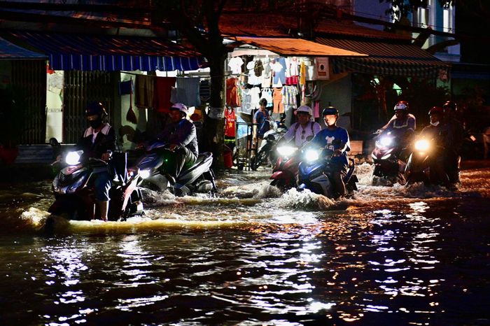  Ở đường Nguyễn Bình, nước ngập khoảng nửa bánh xe. Người dân bì bõm về nhà sau giờ tan làm. Ảnh: Hoài Bảo. 