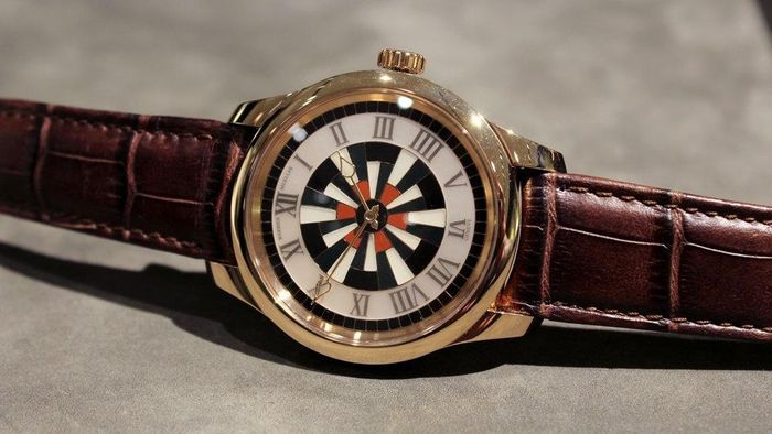  Chiếc đồng hồ sở hữu vỏ vàng hồng 18K, đường kính 41 mm, nổi bật với 136 viên đá jasper mang sắc đỏ gạch, đen, trắng và xanh, được khảm thủ công trên mặt số, vỏ và núm chỉnh giờ. Vòng chỉ giờ làm từ xà cừ, khắc số La Mã, kết hợp bộ kim vàng tạo hình ngọn lửa. Ảnh: Justin Mastine-Frost.