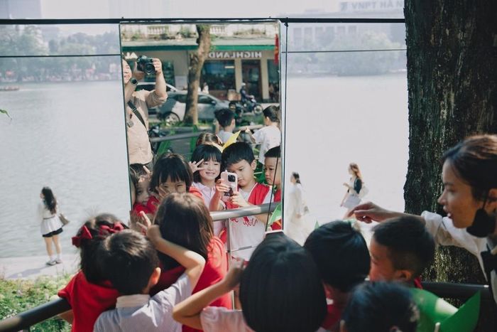 Các em nhỏ hào hứng chụp ảnh lưu niệm qua hệ thống gương nghệ thuật tại không gian “Dải lụa ký ức” bên hồ Hoàn Kiếm trong dịp kỷ niệm 72 năm Ngày Giải phóng Thủ đô. Ảnh: Phạm Tuấn Anh - TTXVN