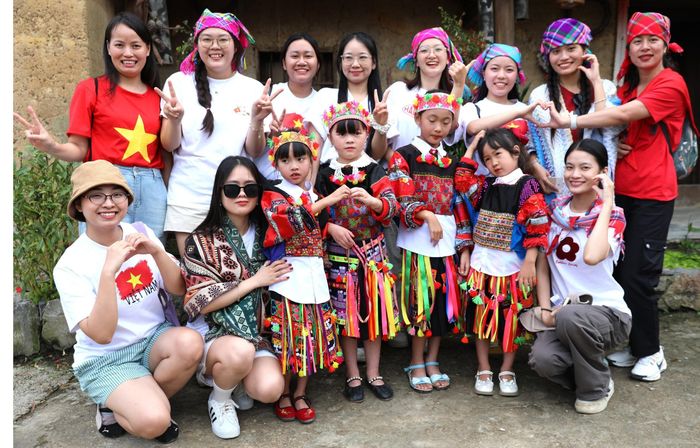 Du khách chụp ảnh lưu niệm cùng các em nhỏ dân tộc Lô Lô ở bản Lô Lô Chải, xã Lũng Cú, tỉnh Tuyên Quang. Ảnh: Minh Tâm-TTXVN