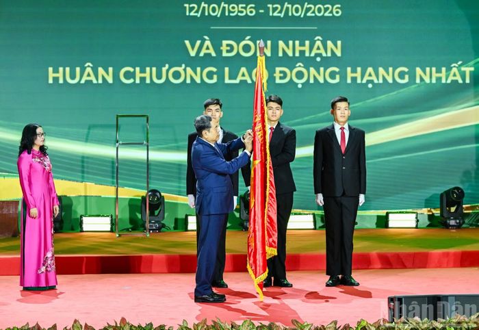 Chủ tịch Quốc hội Trần Thanh Mẫn gắn Huân chương Lao động hạng Nhất lên cờ truyền thống Học viện Nông nghiệp Việt Nam. (Ảnh: DUY LINH)