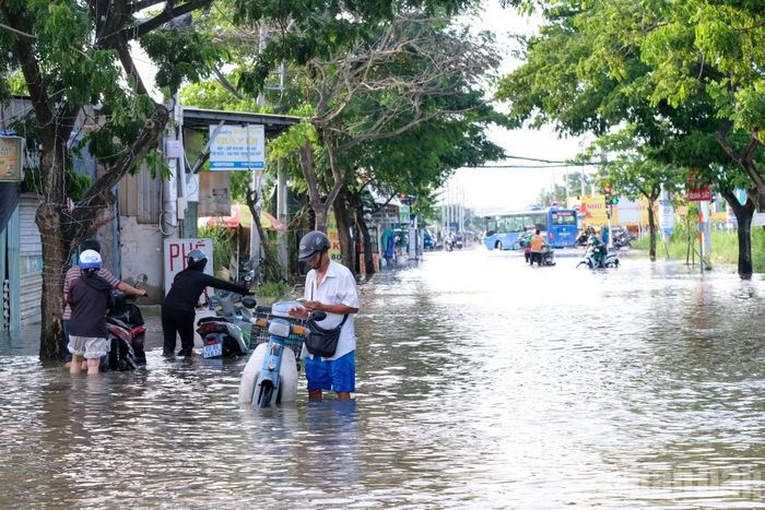Nước ngập lênh láng trên mặt đường Nguyễn Bình, khiến nhiều phương tiện di chuyển qua các khu vực ngập sâu.