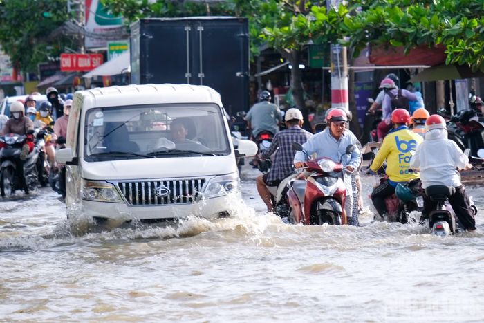 Người dân di chuyển chật vật do triều cường dâng cao trên đường Lê Văn Lương, xã Nhà Bè.