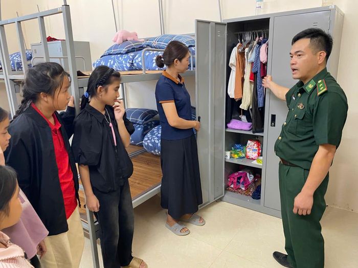 Cán bộ Đồn Biên phòng Yên Khương hướng dẫn học sinh sắp xếp chăn màn và đồ dùng cá nhân. 