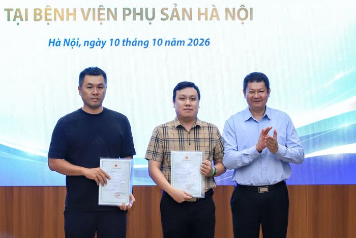 Giám đốc Trung tâm Phục vụ hành chính công TP Hà Nội Phan Văn Phúc trao giấy khai sinh cho đại diện gia đình. Ảnh: THUẬN AN