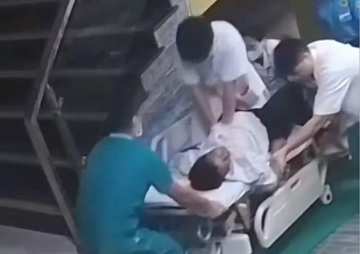 Bác sĩ Quang ngồi trên băng ca cứu thương để ép tim liên tục cho bệnh nhân.