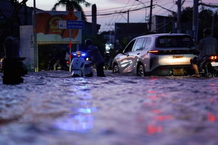 Nước ngập khoảng nửa mét trên đường Nguyễn Bình. Các phương tiện nối đuôi nhau di chuyển chậm qua khu vực ngập kéo dài gần 500m.