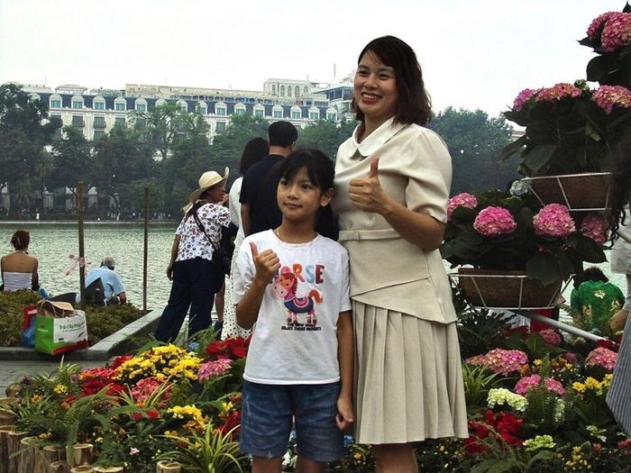 Hai mẹ con cùng ghi lại khoảnh khắc kỷ niệm bên tiểu cảnh hoa ven hồ Hoàn Kiếm.