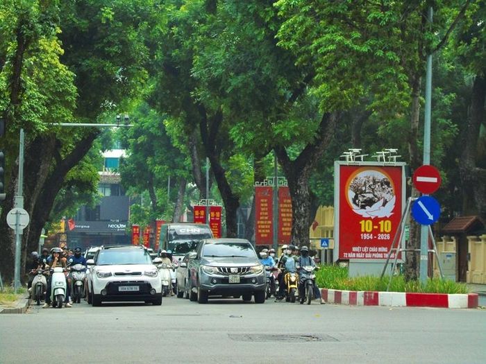 Dòng xe cộ tấp nập qua lại dưới những tán cây xanh rợp bóng cờ hoa tại khu vực trung tâm Hà Nội.