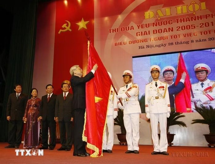 Chủ tịch Quốc hội Nguyễn Phú Trọng gắn Huân chương Sao Vàng lên lá cờ truyền thống của Thành phố Hà Nội tại Đại hội thi đua yêu nước thành phố giai đoạn 2005-2010. (Ảnh : Trí Dũng/TTXVN)