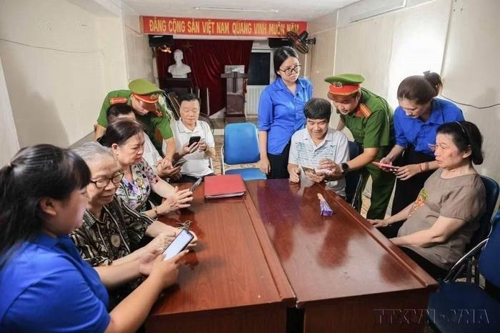 Lực lượng công an, cán bộ tổ dân phố, đoàn viên thanh niên hướng dẫn người dân sử dụng các ứng dụng VNeID, iHanoi... trên điện thoại thông minh. (Ảnh: Hoàng Hiếu/TTXVN)