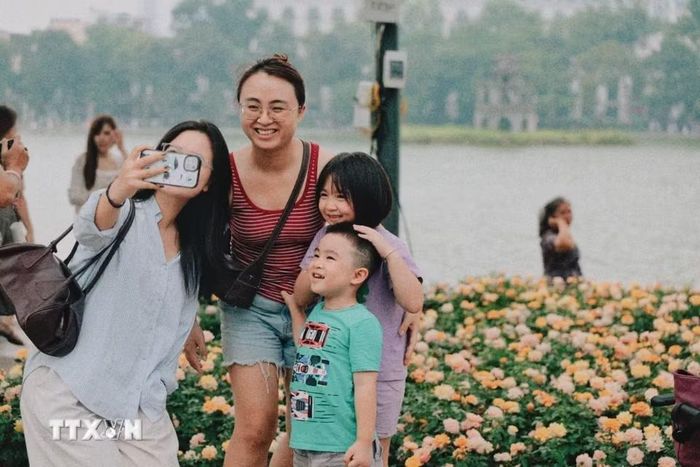 Người dân hào hứng chụp ảnh lưu niệm bên những vườn hoa rực rỡ sắc màu tại khu vực hồ Hoàn Kiếm. (Ảnh: Phạm Tuấn Anh/TTXVN)