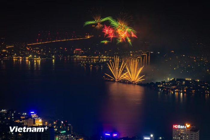 . Những nhịp cầu dây văng đổi màu nhịp nhàng hòa cùng hiệu ứng của những quầng pháo hoa tầm cao bung nở phía trên không trung. Cây cầu như một vệt sáng mềm mại bắt qua sông Hồng, làm nền cho màn trình diễn pháo hoa thêm phần sâu lắng và tráng lệ. (Ảnh: Hoài Nam/Vietnam+)