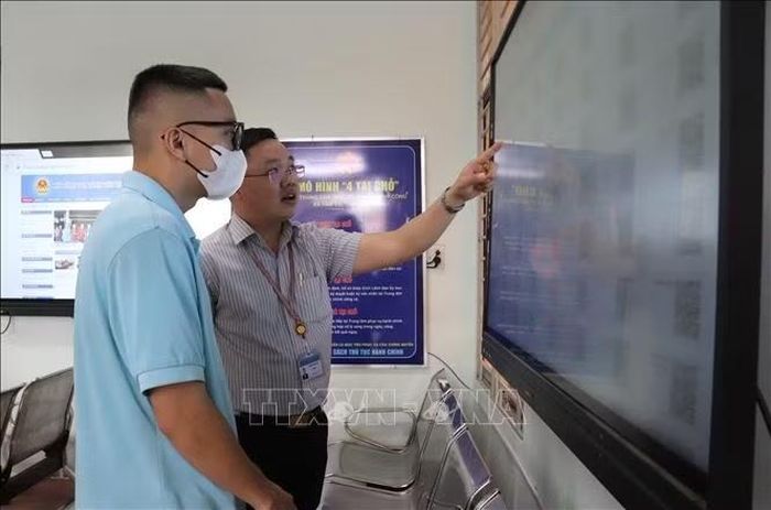 Giám đốc Trung tâm Phục vụ hành chính công xã Tầm Vu - Nguyễn Tuấn Anh hướng dẫn người dân quét mã tra cứu thông tin.
