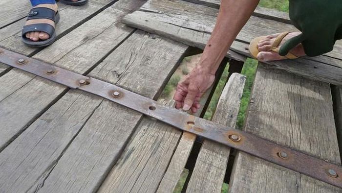 Tấm ván gỗ đã bị mục nát, để lại khoảng hở trên mặt cầu.