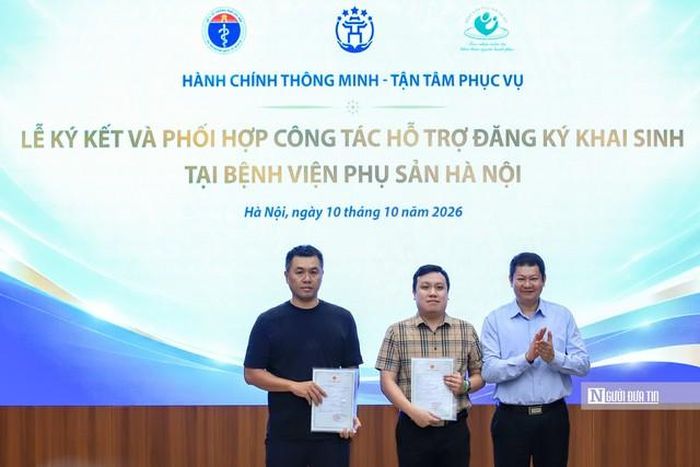 Giám đốc Trung tâm Phục vụ hành chính công Thành phố Hà Nội Phan Văn Phúc trao giấy khai sinh cho 2 gia đình khi hoàn tất thủ tục đăng ký thông qua mô hình thí điểm (Ảnh: Hữu Thắng).