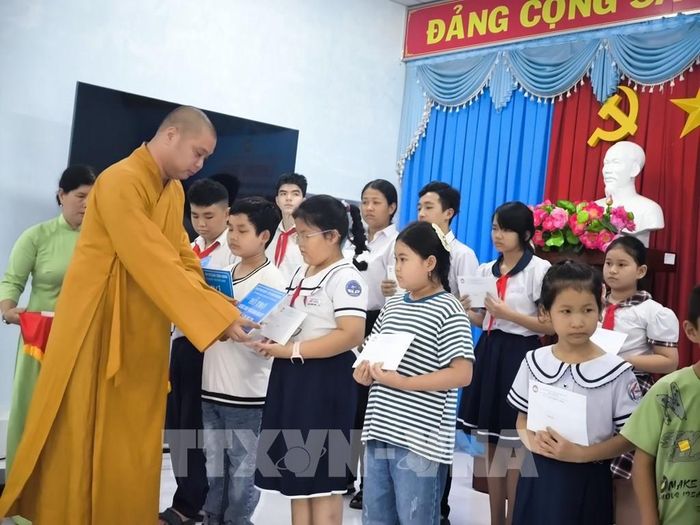 Trao biểu trưng hỗ trợ kinh phí hàng tháng cho trẻ em tại chương trình. Ảnh: Huỳnh Phúc Hậu - TTXVN