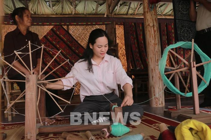 Khách du lịch tham gia trải nghiệm công đoạn quay sợi lanh. Ảnh: Thanh Hà