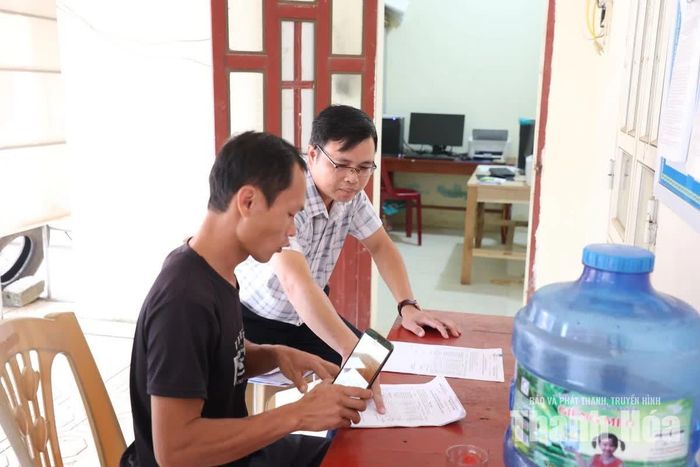 Ông Phạm Minh Thảo, Trưởng phòng Kinh tế xã Luận Thành, hướng dẫn ông Phạm Văn Sơn đối chiếu hồ sơ bồi thường, hỗ trợ tại bàn hướng dẫn bên ngoài hội trường.