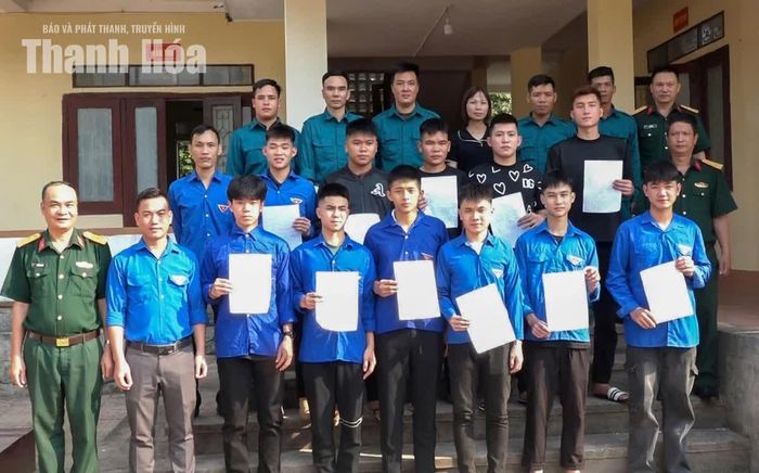 Các thanh niên chụp ảnh lưu niệm với Hội đồng Nghĩa vụ quân sự xã Kim Tân.