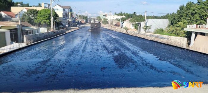 Tưới thấm bám đường đầu cầu mố M1 (phía Đông cầu vượt đường sắt) vào chiều 5/10 để thảm bê tông nhựa. Ảnh: CÔNG TÚ