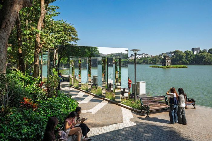 Bên cạnh tuyến cầu cạn, hệ thống cổng gương được bố trí trong không gian vườn cây ven hồ, tạo nên một trải nghiệm thị giác khác biệt. Các cổng gương sử dụng bề mặt phản chiếu để thu nhận và tái hiện hình ảnh của chính môi trường xung quanh như cây xanh, bầu trời, mặt nước, ánh sáng và những người đang di chuyển qua không gian.