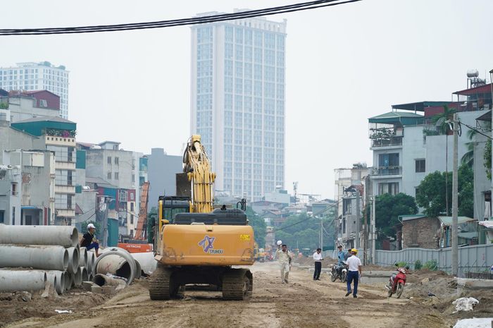 Trên công trường, công nhân cùng máy móc đang thi công nền đường, cống thoát nước và hệ thống hạ tầng kỹ thuật.