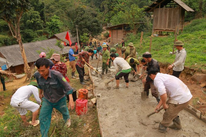 Người dân cùng bộ đội, dân quân đổ bê tông đường vào bản. Ngày công, đất hiến và tinh thần “Nhà nước và nhân dân cùng làm” đã góp phần làm nên diện mạo mới của nông thôn vùng cao. Ảnh: Đình Tuân