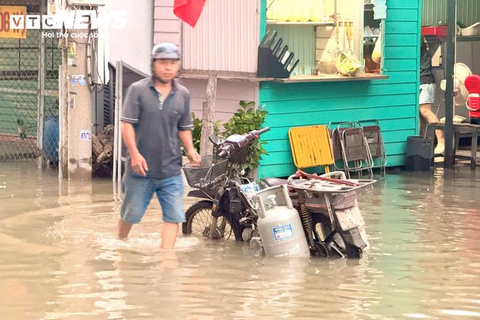 Những người đi làm sớm vất vả lội qua đoạn đường ngập như sông.