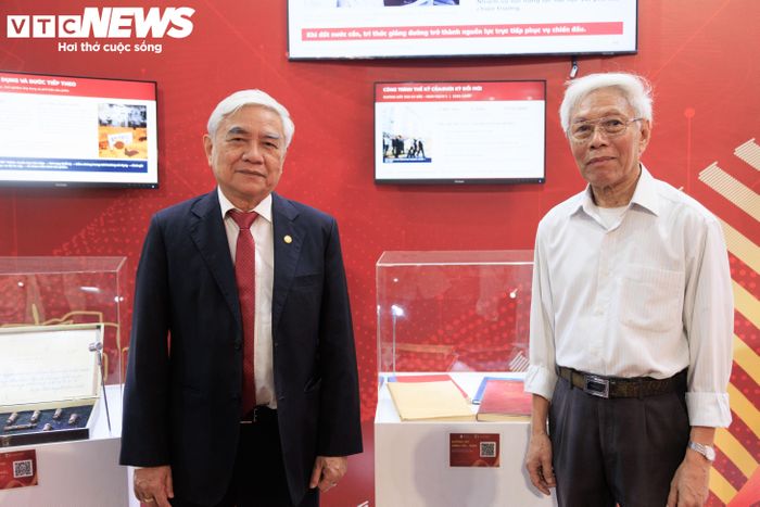 TS. Nguyễn Quân cùng GS.TS. Lã Văn Út chụp ảnh bên cạnh những tài liệu về công trình đường dây siêu cao áp 500kV Bắc - Nam. (Ảnh: Trà My)