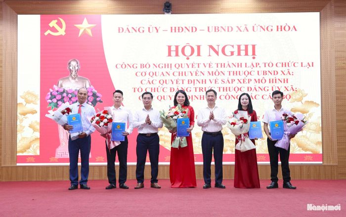 Đồng chí Đàm Văn Huân, Bí thư Đảng ủy, Chủ tịch HĐND xã Ứng Hòa và đồng chí Nguyễn Đức Bình, Phó Bí thư Đảng ủy, Chủ tịch UBND xã Ứng Hòa trao Quyết định và tặng hoa chúc mừng lãnh đạo 5 phòng chuyên môn thuộc UBND xã. Ảnh: Mai Quý