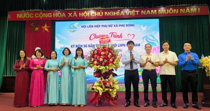 Chủ tịch UB MTTQ Việt Nam xã Phù Đổng Nguyễn Đức Thể cùng các đại biểu tặng hoa chúc mừng Hội LHPN xã Phù Đổng. Ảnh PV