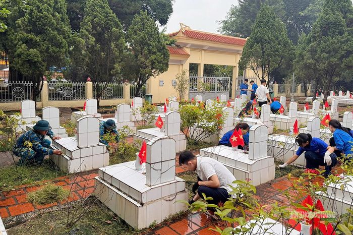 Các chiến sĩ cùng đoàn viên thu gom lá cây, rác thải trong khuôn viên nghĩa trang. Ảnh: Q. Lương