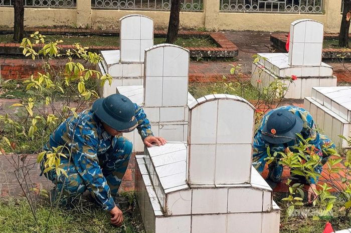 Chiến sĩ Tiểu đoàn 172 nhổ cỏ, làm sạch khu vực quanh các phần mộ. Ảnh: Q. Lương