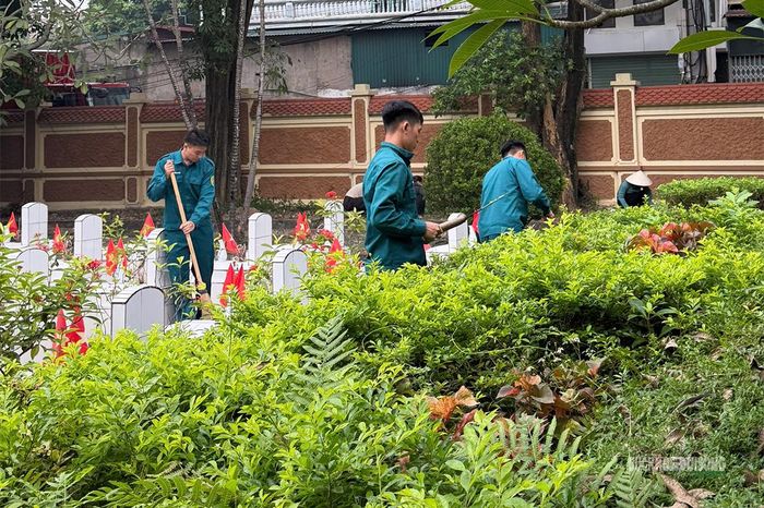 Bộ đội, dân quân và đoàn viên thanh niên cùng chăm sóc các phần mộ liệt sĩ. Ảnh: Q. Lương