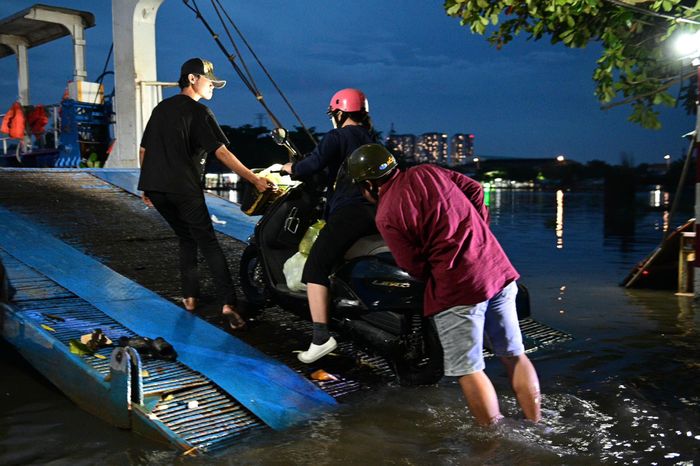  Tại bến phà Phú Định, phía bờ đường Rạch Cùng (phường Bình Đông), nước triều dâng cao khiến việc đưa xe máy lên phà gặp nhiều khó khăn. Trong khi nước phủ kín khu vực tiếp giáp giữa đường và bến phà. 