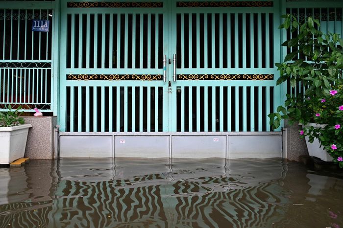  Người dân tại khu dân cư ven đường Rạch Cùng phải lắp tấm chắn trước cửa, đồng thời bật máy bơm liên tục để ngăn nước triều tràn vào nhà. 