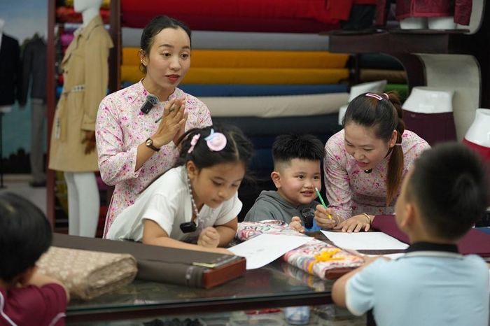 Các cô thợ may ở Hội An hướng dẫn các con vẽ thiết kế quần áo cho các bố