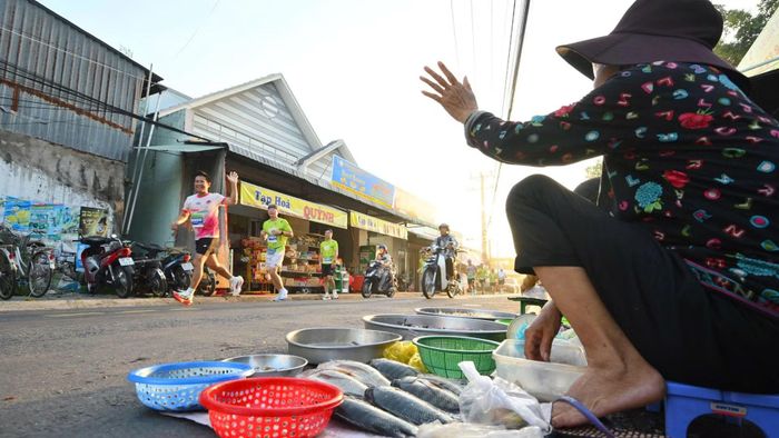 Vận động viên và tiểu thương ở một chợ nông thôn vẫy tay chào nhau. (Ảnh: Ban tổ chức)
