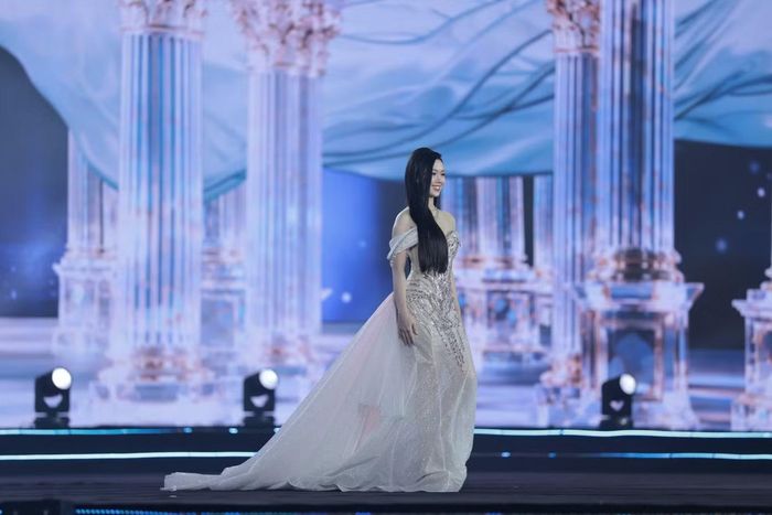 Vũ Thị Khánh Vi diện đầm dạ hội với thiết kế trễ vai, họa tiết đính kết chạy dọc thân váy và phần tà dài thướt tha.