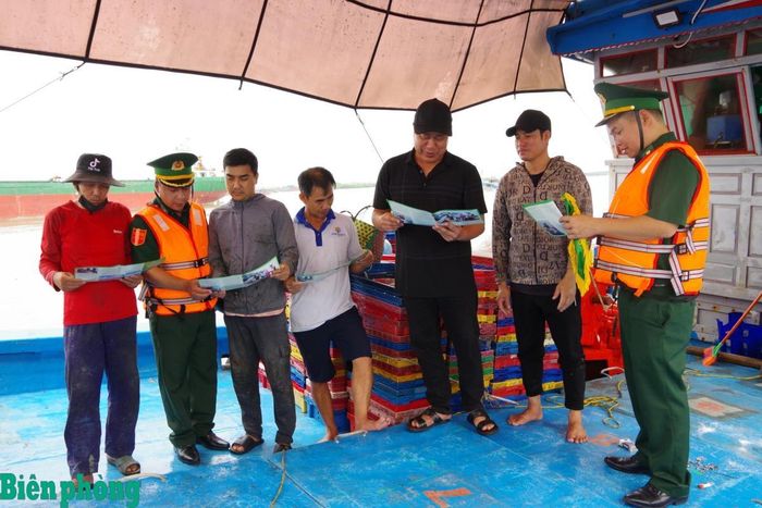 Cán bộ Bộ đội Biên phòng tỉnh Ninh Bình phát tờ rơi tuyên truyền, phổ biến, giáo dục pháp luật cho ngư dân. Ảnh: Minh Khôi