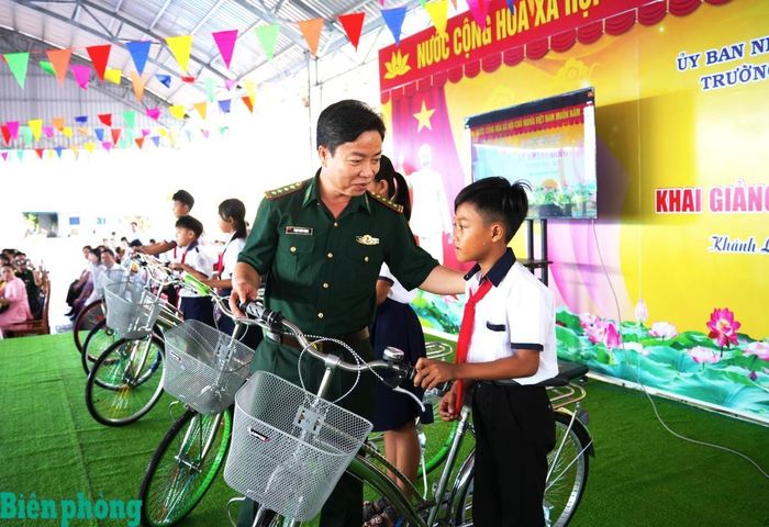 Đại tá Phạm Minh Giang, Chính ủy Ban Chỉ huy Bộ đội Biên phòng tỉnh Cà Mau trao học bổng, xe đạp cho học sinh Trường Tiểu học Kim Đồng được đơn vị nhận đỡ đầu theo Chương trình “Nâng bước em tới trường - Con nuôi đồn Biên phòng” nhân dịp khai giảng năm học mới. Ảnh: Hoàng Tá