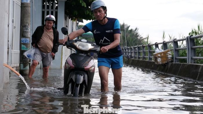 Nước ngập sâu khiến người dân di chuyển khó khăn. Một số người phải xuống xe, dắt bộ qua những đoạn nước ngập sâu.