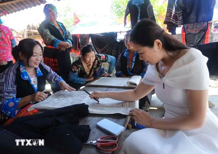 Du khách trải nghiệm kỹ thuật tạo hoa văn trên vải lanh của phụ nữ dân tộc Mông tại bản Tù Lu-Tìa Ló. (Ảnh: Xuân Tư/TTXVN)