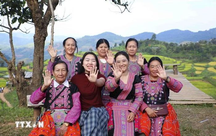 Du khách và đồng bào dân tộc Mông vùng cao mời gọi du khách đến tham quan ruộng bậc thang Pu Nhi. (Ảnh: Xuân Tư/TTXVN)