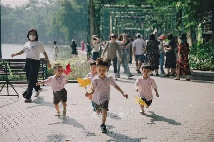 Các em nhỏ vui đùa với chong chóng tại không gian hồ Hoàn Kiếm. Ảnh: Phạm Tuấn Anh/TTXVN