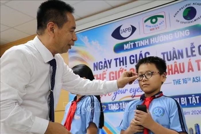 Thầy thuốc Nhân dân, Tiến sĩ, Bác sĩ Nguyễn Viết Giáp, Giám đốc Bệnh viện Mắt Bà Rịa-Vũng Tàu trao kính cho học sinh mắc tật khúc xạ có hoàn cảnh khó khăn tại khu vực xã Long Hải và xã Long Điền. Ảnh: Huỳnh Sơn/TTXVN