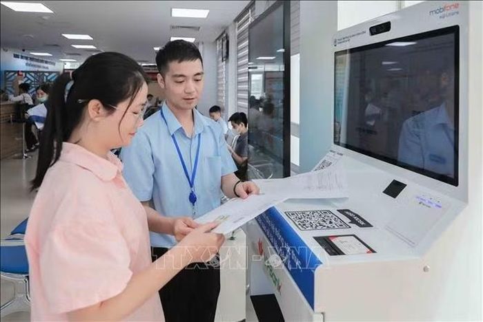 Cán bộ Chi nhánh số 6 Trung tâm Phục vụ hành chính công Hà Nội tại xã Gia Lâm hướng dẫn người dân dùng Ki ốt AI cấp bản sao số điện tử miễn phí, dùng trọn đời. Hệ thống giúp thao tác một lần, kết quả tự động tích hợp vào ví iHanoi mà không cần gặp trực tiếp cán bộ chuyên trách. Ảnh: Phan Phương/TTXVN